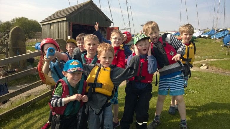 Cubs and Beavers in buoyancy aids beside a boat shed at a sailing centre