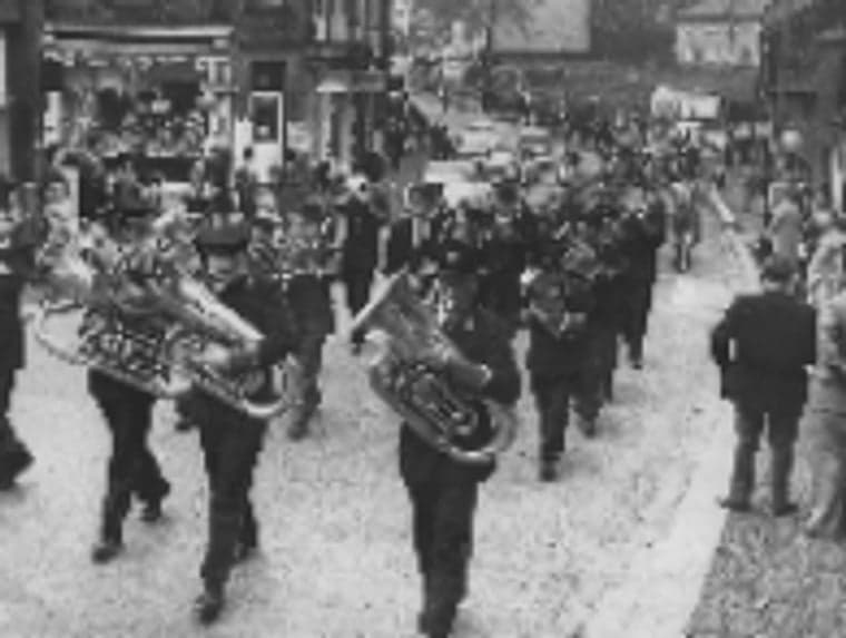 A black-and-white photograph of a brass band leading a parade through the streets of Otley